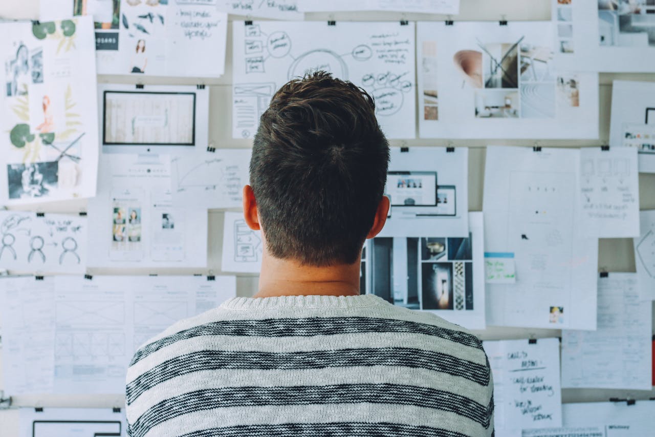 A man stands in front of a wall filled with creative ideas and plans. Ideal for innovation themes.